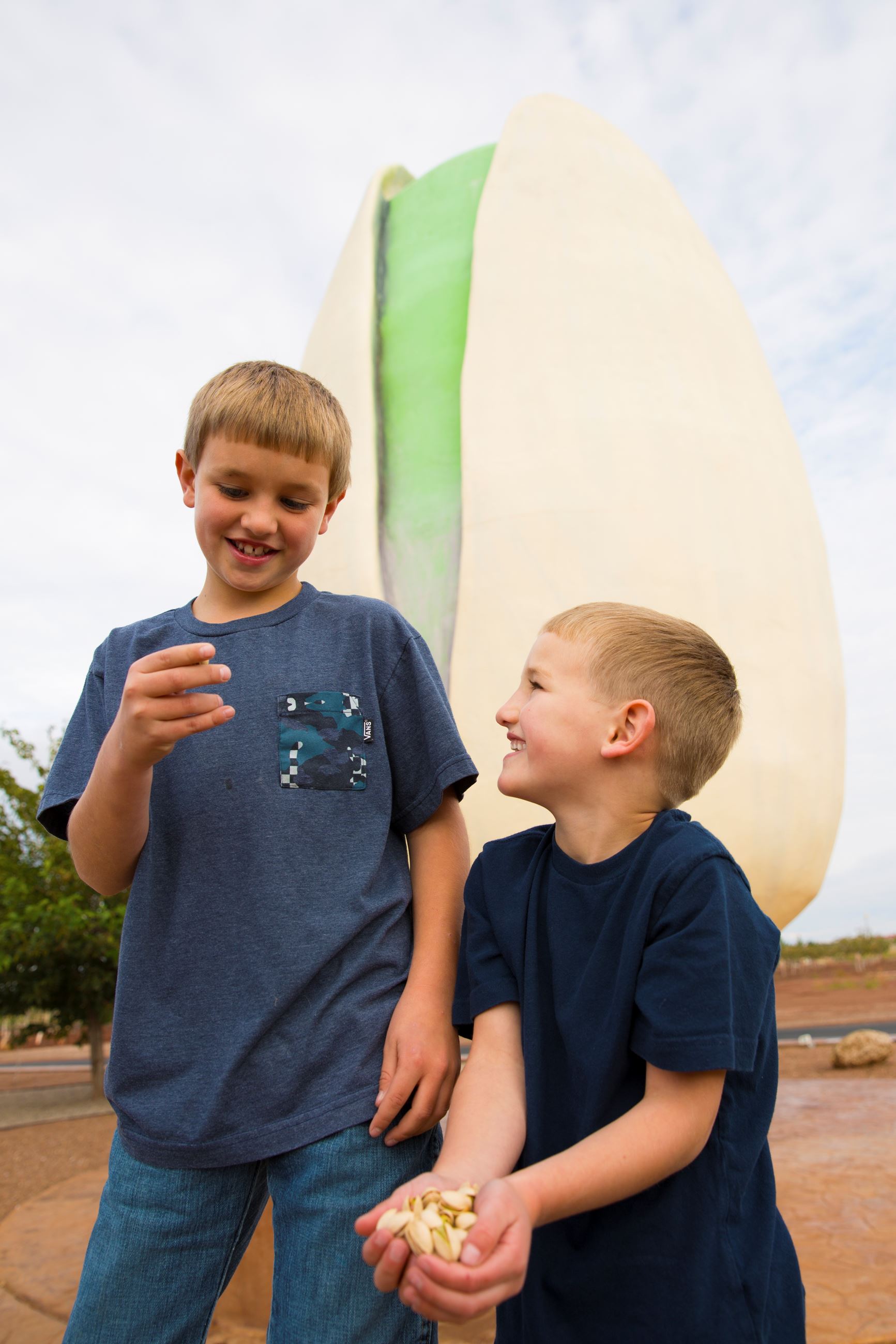 Two young boys in blue shirts in front of the world's largest pistachio.