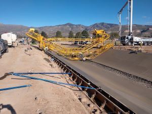 Equipment and workers in a cement ditch with mountains in the background